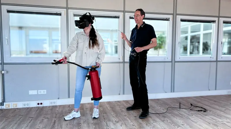 Melanie übt mit VR-Brille und Löscher, Rüdiger leitet an
