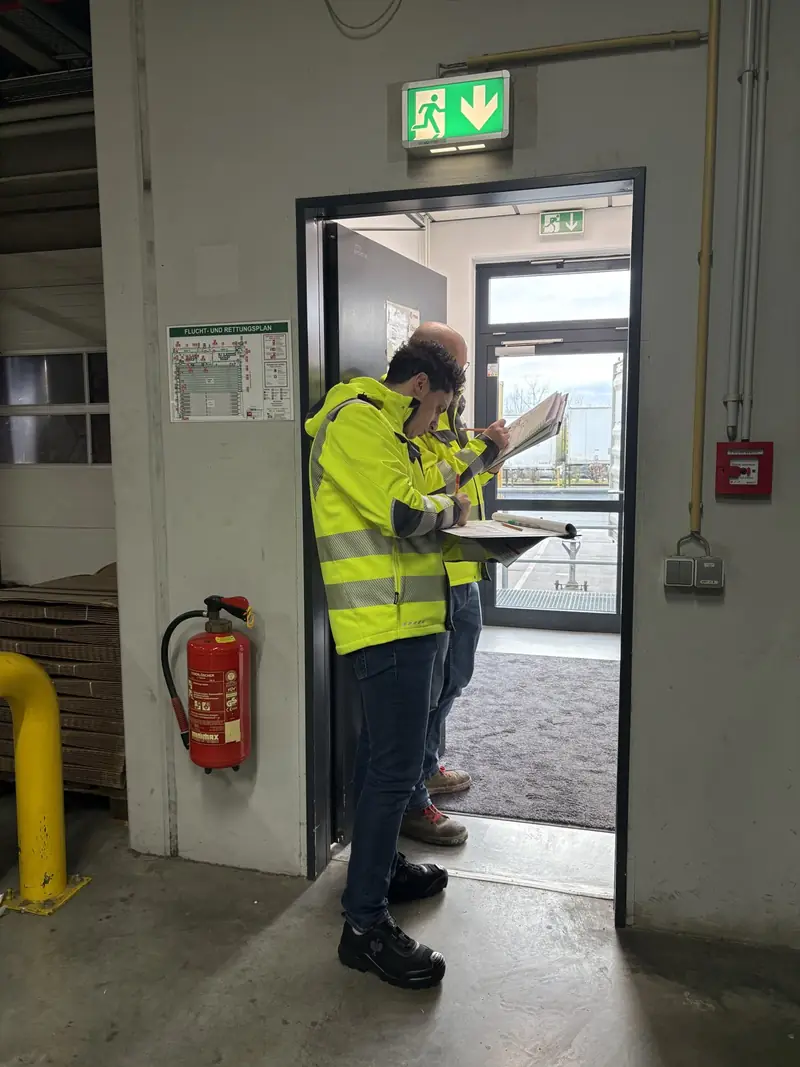 Fachkraft für Arbeitssicherheit prüft bei einer Begehung den Notausgang