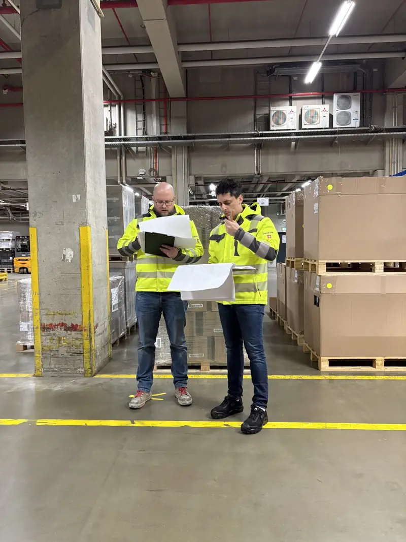 Zwei Fachkräfte in Warnweste bei einer Begehung in einer Logistikhalle