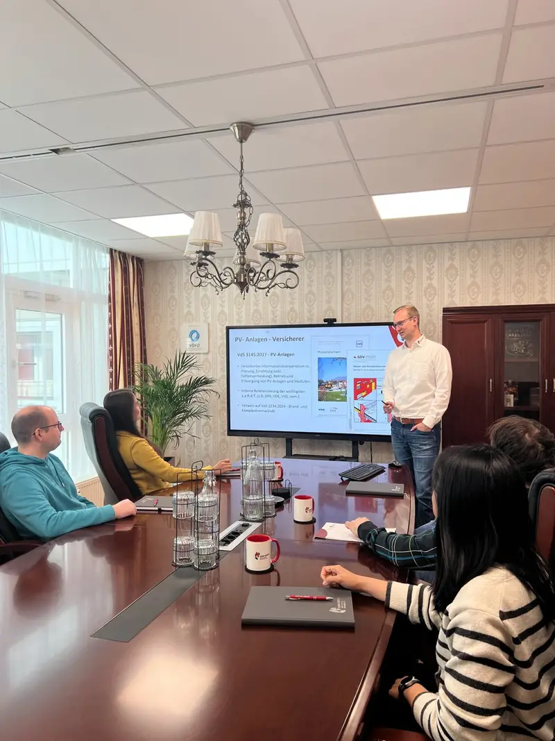 Besprechung am Konferenztisch mit Präsentation auf dem Bildschirm