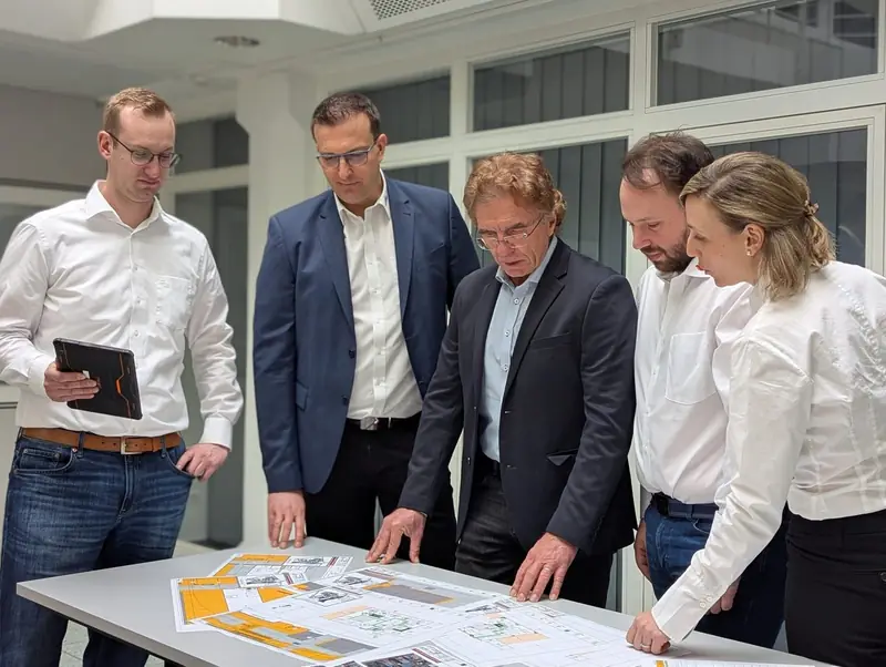 Planbesprechung im Team am Tisch mit ausgedruckten Brandschutzplänen