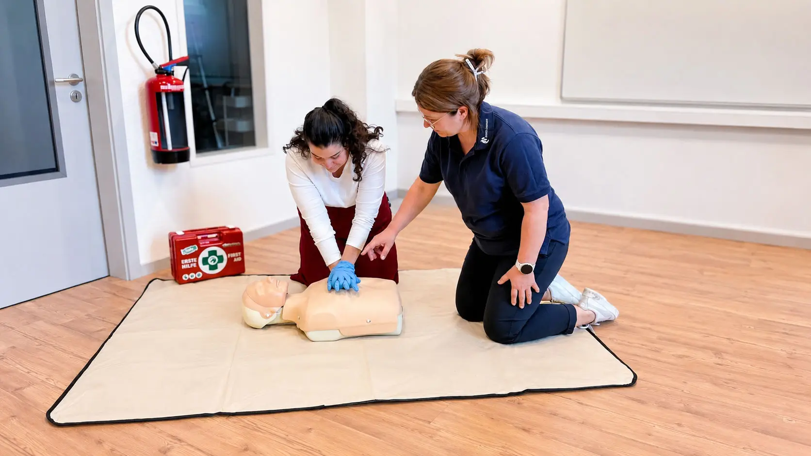 EHBS-Ausbilderin trainiert Herzdruckmassage mit einer Kursteilnehmerin an einer Übungspuppe