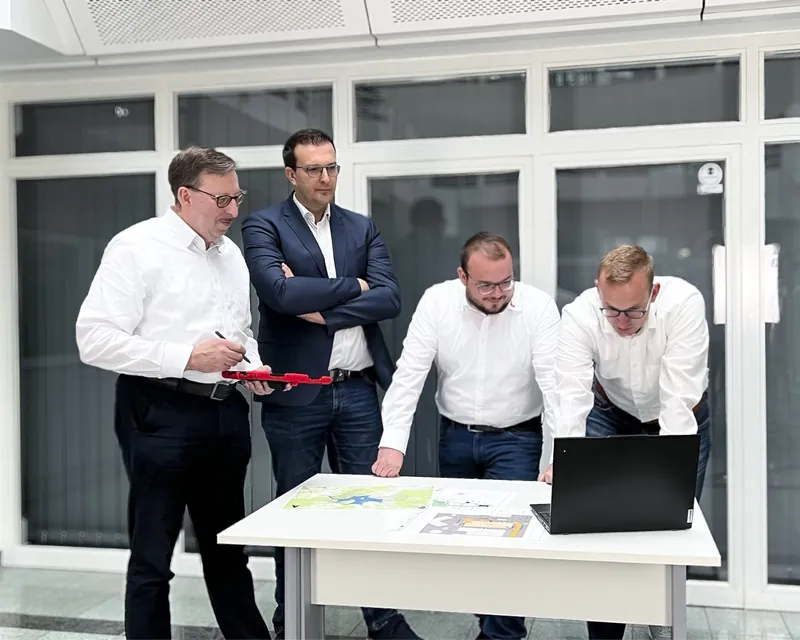 Vier Personen aus dem Team von EHBS Knecht besprechen ausgelegte Karten an einem Tisch mit Laptop