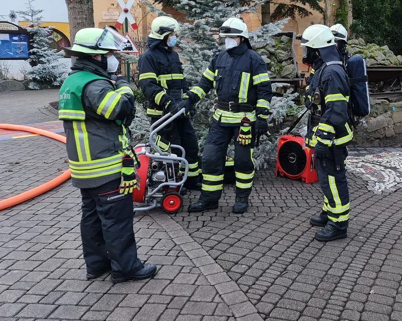 Einsatzkräfte einer Werkfeuerwehr mit Atemschutz, Drucklüfter und Schlauchleitungen bei einer Übung